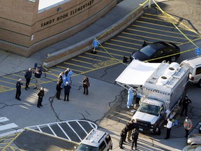 In this Dec. 14, 2012, file photo, officials stand outside of Sandy Hook Elementary School after a shooting in Newtown, Conn.