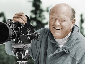 In this undated photo provided by the Warren Miller Co., Warren Miller is shown posing for a photo with a film camera. (Warren Miller Co. via AP)