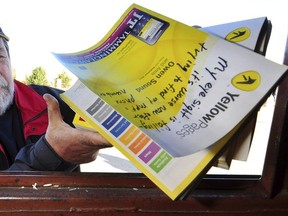 MPP Bill Murdoch throws some of the 300 Yellow Pages phone books people have dropped off at his Owen Sound constituency office into a recycling bin.