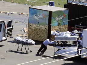 In this Oct. 2, 2017, file photo, investigators load bodies from the scene of a mass shooting at a music festival near the Mandalay Bay resort and casino on the Las Vegas Strip in Las Vegas.
