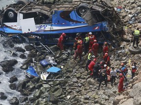 In this photo provided by the government news agency Andina, firemen recover bodies from a bus that fell off a cliff after it was hit by a tractor-trailer rig, in Pasamayo, Peru, Tuesday, Jan 2, 2018. A Peruvian police official says at least 25 people died, and that there were more than 50 people on the bus.