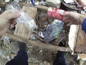 This frame grab pulled from body camera footage that was filmed Jan. 24, 2017, and released by the Maryland Office of the Public Defender shows Baltimore Police Officer Richard Pinheiro removing a baggie of drugs from a soup can in Baltimore. (Baltimore Police Department via AP)