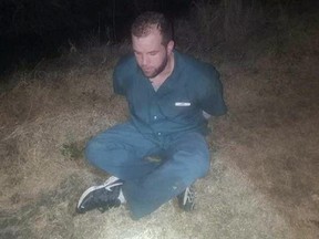 This photo provided by the Jefferson County Sheriff's Office in Beaumont, Texas, shows Joshua Hansen sitting in a field after his arrest Wednesday, Jan. 24, 2018. (Jefferson County Sheriff's Office via AP)