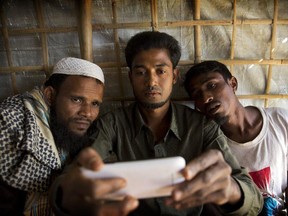 In this Jan. 14, 2018 photo, Rohingya Muslim refugee Mohammad Karim, 26, centre, shows a mobile video of Gu Dar Pyin's massacre to other refugees in Kutupalong refugee camp, Bangladesh.