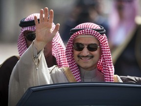 FILE - In this Feb. 4, 2014 file photo, Saudi billionaire Prince Alwaleed bin Talal waves as he arrives at the headquarters of Palestinian President Mahmoud Abbas in the West Bank city of Ramallah. Three associates of Saudi Prince Alwaleed bin Talal say the billionaire investor has been released after nearly three months in detention at a luxury hotel as part of an anti-corruption sweep. The associates told The Associated Press that the prince was released on Saturday Jan. 27, 2018.