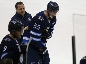 Winnipeg Jets centre Mark Scheifele clutches his right shoulder as he is helped to the bench during NHL action against the Edmonton Oilers last night. Kevin King/Winnipeg Sun