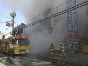 Firefighters work as smoke billows from a hospital in Miryang, South Korea, Friday, Jan. 26, 2018.
