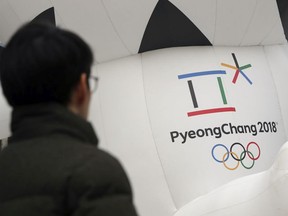 In this Dec. 29, 2017, photo, a man walks by the official emblem of the 2018 Pyeongchang Olympic Winter Games, in downtown Seoul, South Korea.