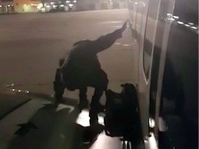 A Ryanair passenger who apparently got fed up waiting to get off a plane stands on the wing of a Ryanair plane at Malaga airport, Spain, Monday Jan. 1, 2018, filmed by another passenger.  After various delays in the flight from London's Stansted Airport, the passenger, who has not been named, used the emergency exit to climb onto the wing after landing in Spain New Year's Day. (Fernando del Valle Villalobos via AP)