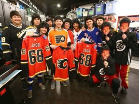 Members of the Travelling Jagrs receive freshly printed Flames jerseys during a promotional stop at the Chinook Centre Sport Chek location in Calgary on Oct. 7, 2017.
