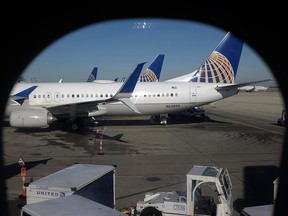 In this Nov. 22, 2017, photo taken through an aircraft passenger window, United Airlines planes are parked at a terminal at O'Hare International Airport in Chicago. (AP Photo/Kiichiro Sato)