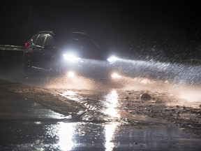 A car makes its way along Shore Road, strewn with rocks and debris tossed up by waves, in Eastern Passage, N.S. on Jan. 4, 2018. Atlantic Canada has been hit with fierce winds, rain and heavy snow to being the new year.