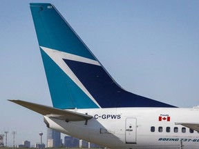 The tail of a WestJet plane dwarfs the Calgary skyline before the airline's annual meeting in Calgary, Tuesday, May 3, 2016.