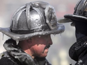 In this Feb. 12, 2012, file photo, a firefighter's helmet is caked in ice at the scene of a four-alarm fire in Boston. Cold-weather fire departments prepare months ahead for winter's coming freeze, readying equipment and changing how they approach fires in the coldest months.