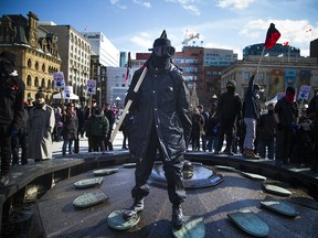 Anti-Muslim and anti racist protestors voiced their views Sunday Feb. 18, 2018 on Parliament Hill. An anti racist protestors stands in the Centennial Flame. Ashley Fraser/Postmedia