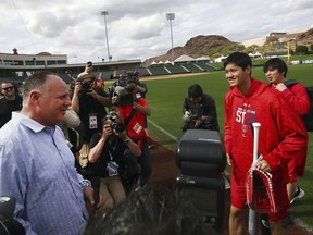 Los Angeles Angels' Shohei Ohtani, second from right holding bat, speaks with coach Mike Scioscia during a spring training baseball practice on Tuesday, Feb. 13, 2018, in Tempe, Ariz.