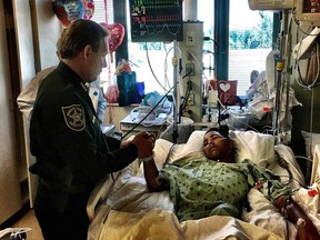 A member of the Broward Sheriff's Office visits Anthony Borges, 15, in hospital. The teen was shot five times (Broward Sheriff's Office Facebook)
