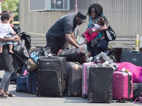 Asylum seekers sort out their luggage at a processing centre after crossing the border into Canada from the United States Monday, August 21, 2017 near Saint-Bernard-de-Lacolle, Que.