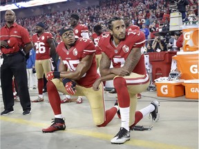 Colin Kaepernick, right, kneels beside teammate Eric Reed during the performing of the national anthem before the San Francisco 49ers NFL game on Sept. 12, 2016.