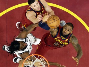 Cleveland Cavaliers' LeBron James grabs a rebound ahead of Brooklyn Nets' DeMarre Carroll as Larry Nance Jr. watches during an NBA game on Feb. 27, 2018