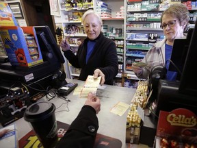 In this Jan. 7, 2018, file photo, cashiers Kathy Robinson, left, and Ethel Kroska, right, both of Merrimack, N.H., sell a lottery ticket at Reeds Ferry Market convenience store in Merrimack.
