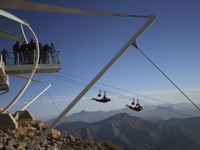 In this Wednesday, Jan. 31, 2018 photo, thrill-seekers ride from the UAE's highest mountain as they try out a new zip line, on the peak of Jebel Jais mountain, 25 kms (15.5 miles) north east of Ras al-Khaimah, United Arab Emirates. The UAE is claiming a new world record with the opening of the world's longest zip line, measuring 2.83 kilometers (1.76 miles) in length. Guinness World Records officials certified the zip line on Thursday, the same day the attraction opened to the public.