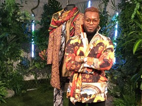 Wale Oyejide, founder of the brand Ikire Jones, stands with his menswear design for a fashion collection inspired by the superhero film "Black Panther," Monday, Feb. 12, 2018, in New York. The designs will be auctioned to benefit the charity Save the Children.