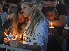 Mourners gather at a vigil that was held for the victims of the shooting at Marjory Stoneman Douglas High School in Parkland, Fla.