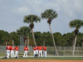 Members of the Miami Marlins pause before stretching during spring training baseball practice Wednesday, Feb. 14, 2018, in Jupiter, Fla.