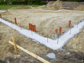 In this stock photo, a house basis sits on a lot with the pipes emerging from the ground.