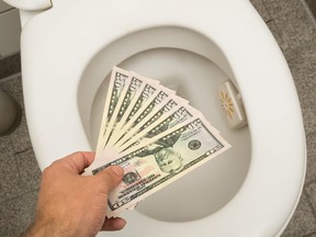 In this stock photo, a man flushes U.S. $50 bills down the toilet.