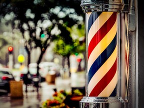 In this stock photo, a barbershop pole sits outside a store.