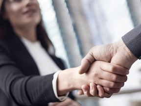 In this stock photo, a female businesswoman shakes hands with a male counterpart.