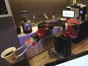 Robot barista named "Sawyer" makes a coffee at Henna Cafe, Japanese meaning "Strange Cafe"in Tokyo, Friday, Feb. 2, 2018. The cafe's robot barista brews and serves coffee as the rapidly aging country seeks to adapt to shrinking workforce.  (AP Photo/Koji Sasahara)