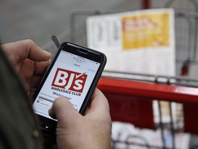 In this Tuesday, Feb. 13, 2018 photo Tony D'Angelo logs into the stores Wi-Fi to download the BJ's Express Scan app on his cell phone before beginning his shopping at the BJ's Wholesale Club in Northborough, Mass. More stores are letting customer tally their choices with a phone app or store device as they roam the aisles. For customers, scanning as they go can be faster and make it simpler to keep track of spending.