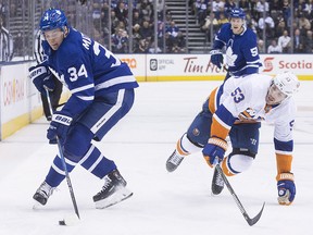 Toronto Maple Leafs' Auston Matthews (left) takes the puck away from New York Islanders' Casey Cizikas in Toronto, on Thursday, February 22, 2018. (THE CANADIAN PRESS/Chris Young)
