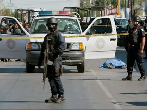 Members of the Federal Police secure the street as the body of a municipal police officer lies dead in Ciudad Juarez, Mexico, on Sept. 7, 2010. Prosecutors in northern Mexico say five headless bodies have been left in front of a funeral home this week.