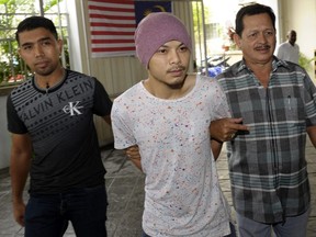 Wee Meng Chee, centre, a Malaysian rapper popularly known as Namewee, is escorted by plainclothes policemen as he arrives at the magistrate court in Penang, Malaysia, Aug. 22, 2016. The rapper was detained Thursday, Feb. 22, 2018 for allegedly insulting Islam in his latest music video.