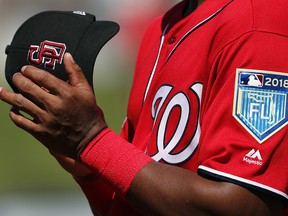 A member of the Washington Nationals holds his cap as Marjory Stoneman Douglas High School student Angelique Meneses sings the national anthem before the start of spring training game against the Houston Astros, Friday, Feb. 23, 2018, in West Palm Beach, Fla. (AP Photo/Jeff Roberson)