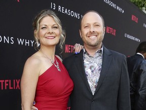 In this March 30, 2017 photo, Joan Marie and Author Jay Asher appear at the Netflix "13 Reasons Why" premiere in Los Angeles. A planned second season of "Thirteen Reasons Why" on Netflix will be unaffected by the recent allegations of sexual harassment against author Jay Asher. Netflix said in a statement Tuesday that Asher was uninvolved in the new season.  On Monday, the Society of Children's Book Writers and Illustrators told The Associated Press that Asher had been kicked out of the organizations because of complaints about harassment.