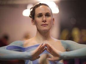 This photo provided by Andy Golub shows a  nude model getting ready to take part in the Polar Bear Paint body-painting event in the rain and cold of New York City's Times Square holds still while being painted on Saturday Feb. 10, 2018. (Andy Golub via AP)