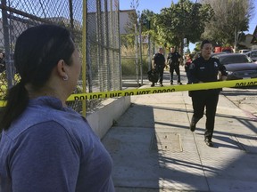 Gloria Echeverria watches as Los Angeles police officers close off a street where a shooting occurred at a middle school in Los Angeles on Thursday, Feb. 1, 2018.