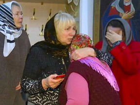 In this video grab provided by the RU-RTR Russian television  a group of believers comfort each other after a memorial service in the Russian Orthodox Church in Kizlyar, Russia, Monday, Feb. 19, 2018. The Islamic State group has claimed responsibility for a deadly attack on churchgoers in Russia's predominantly Muslim Dagestan region. At least five people were killed and four wounded when a gunman opened fire with a hunting rifles on people leaving a Sunday service at a Russian Orthodox church in the Dagestan city of Kizlyar. (RU-RTR Russian Television via AP) ORG XMIT: XAZ106