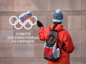 In this file photo taken on Dec. 5, 2017 A supporter waves a Russian flag in front of the logo of the International Olympic Committee at their headquarters in Pully near Lausanne