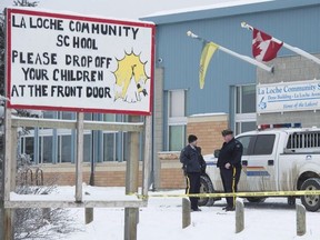 Members of the RCMP stand outside the La Loche Community School in La Loche, Sask. Monday, Jan. 25, 2016.