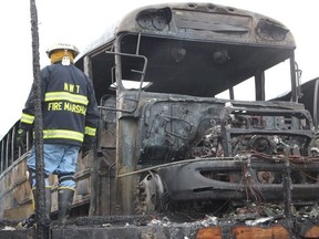 A firefighter clears wreckage from a school bus depot in South Whitehall, Pa.,, that was destroyed by fire ion Friday, Feb. 23, 2018.