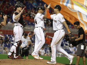 In this May 26, 2017, file photo, Miami Marlins catcher J.T. Realmuto, left, relief pitcher AJ Ramos, left, and right fielder Giancarlo Stanton, right, celebrate after defeating the Los Angeles Angels in Miami.