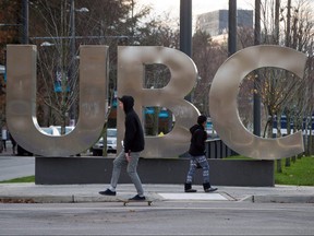 A man on a skateboard and a young woman pass large letters spelling out UBC at the University of British Columbia in Vancouver on Nov. 22, 2015.