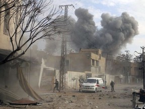 This photo provided by the Syrian Civil Defence White Helmets, which has been authenticated based on its contents and other AP reporting, shows a plume of smoke rises while civil defence workers arrive at the scene of an attack after airstrikes hit a rebel-held suburb near Damascus, Syria, Thursday, Feb. 8, 2018.