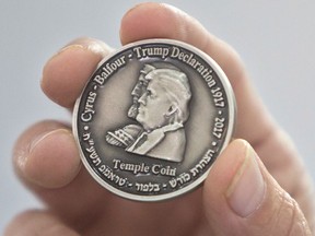 Head of the Mikdash Educational Center, Rabbi Mordecahi Persoss, holds a coin they minted bearing U.S. President Donald Trump's image to honour his recognition of Jerusalem as Israel's capital, in Tel Aviv, Israel, Wednesday, Feb. 28, 2018. (AP Photo/Sebastian Scheiner)